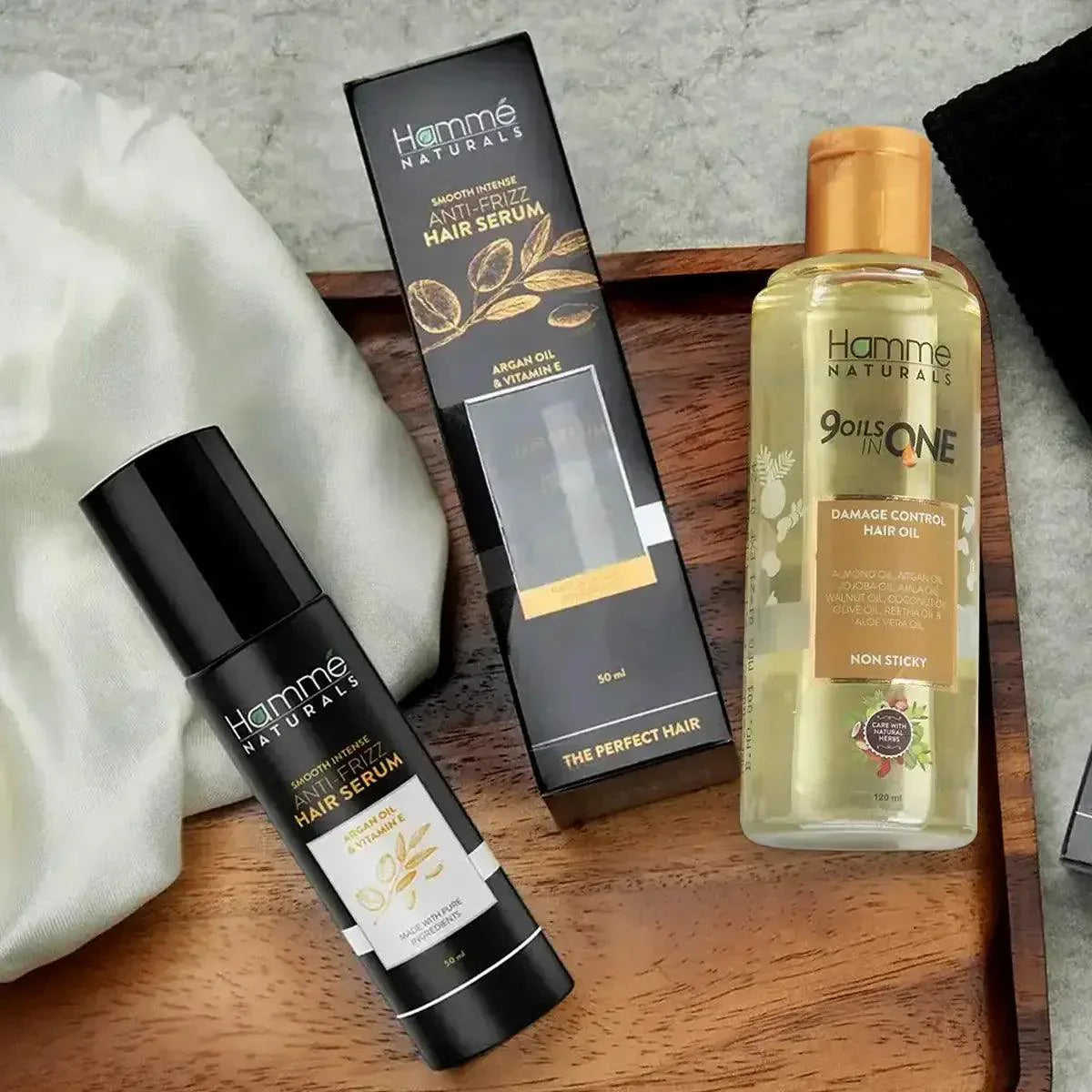 Hair Repair and Restore Duo - Hammé - Makes You Stand out  - A bottle of Hamme Naturals Anti-Frizz Hair Serum and a 9-in-1 hair oil displayed elegantly on a tray